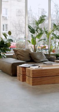 Rahat deri koltuklar ve ahşap masalar. Doğal ışıklandırması ve modern mobilyaları olan şık bir apartman dairesi. Kitaplar ve bitkiler rahat ve rahatlatıcı bir atmosfer yaratırlar..