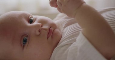 Bebek bezi takmış, yatakta uzanmış kameraya bakan tatlı bir bebek. Beşikte komik suratlı yeni doğmuş bir bebek. Tombul yanakları ve büyük mavi gözleri olan sevimli yeni doğmuş çocuk vücudunu hareket ettiriyor ve kameraya bakıyor..