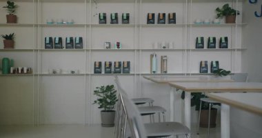 Zarif ve minimalist bir kafenin içinde markalı ürünlerle dolu raflar ve şık ahşap masalar var. Rahatlamak ya da sıradan iş toplantıları için mükemmel bir ortam.