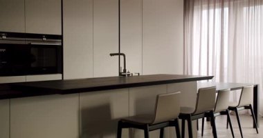 Çağdaş bir mutfak vitrininde minimalist tasarım, temiz çizgiler, koyu bir tezgah ve beyaz dolaplar sergilenir. Zarif Tasarımlı Modern Mutfak Özellikleri ve Zarif Basitliği