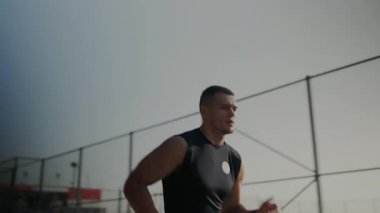 Kendini adamış genç bir erkek sporcu akşam vakti bulanık doğal ortamında odaklanmış ve kararlılıkla dışarı koşuyor. Dusk 'ta Açık havada Koşu Çalışması Yaparken Odaklanmış Sporcu