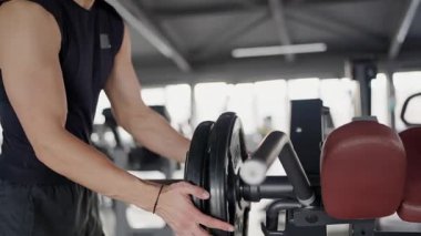 Odaklanmış görüntü, el ele tutuşmalar ağırlık kaldırmalar, spor salonunda antrenman yapmaya hazırlanmalar. Spor salonundaki halterlere ağırlık yükleyen ellerin yakın çekimi
