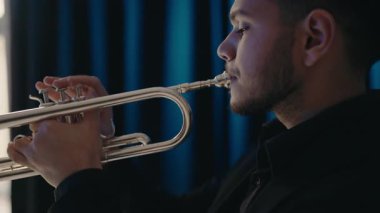 Takım elbiseli genç ve yakışıklı bir adam arzu ve ilhamla trompet çalar. Canlı caz konseri. Müzik tutkusu. Genç trompetçinin yakın eli. Müzik odası.