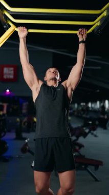 Modern bir spor salonunda barfiks çeken kaslı bir adam. Her tekrarı tamamlarken güç, uygunluk ve kararlılık gösteriyor. Jimnastik salonu atmosfere enerji katıyor..