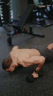 Modern bir spor salonunda kaslı bir adam halterli şınav çeker. Formuna ve gücüne odaklanıyor, fitness 'e olan bağlılığını gösteriyor. sağlıklı yaşam tarzı ve egzersiz hedefleri.