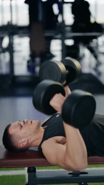 Kas yığını bir adam modern bir spor salonunda ağırlık kaldırıyor. Formuna ve nefesine odaklanıyor. Gücünü ve uygunluğunu gösteriyor. sağlıklı yaşam tarzı ve egzersiz rutini.