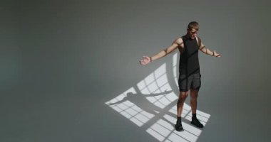 Atletik bir adam bir stüdyo içinde fiziksel antrenman yapar. Formda olduğunu gösterir. Stüdyoda Genç Atletizm Eğitimi, Spor ve Sağlık Konsepti