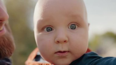 Tuhaf bakışları olan bir bebeğin sevimli yakın çekimi, bulanık bir arka plan üzerine kurulmuş. Sıcak ve çekici duygular resmedilmiş. Bir bebeğin yakından çekilmiş portresi ilginç bir şekilde dışarı bakıyor.