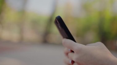 Bir el ele tutuşmanın yakın plan odaklı görüntüsü ve açık hava ortamında çok bulanık bir arka planı olan bir akıllı telefon kullanımı. Açık Hava Bulanık Ayarında Elle Tutma Smartphone 'unun Yakın Çekimi