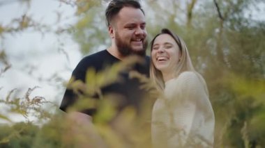 Mutlu bir çift birlikte güler sakin bir açık havada, sonbaharda sevgi ve mutluluk gösterirler. Sevgi dolu çift Doğada Sıcak bir Sonbahar Gününün tadını çıkarıyor