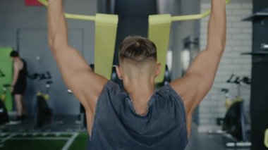 Spor salonundaki bir makinede egzersiz yapan bir adamın arka görüntüsü. Spor aletlerine, spor aletlerine ve sağlıklı bir yaşam tarzına odaklan. Spor salonunda spor salonunda spor yapan bir adam spor salonuna odaklanıyor.