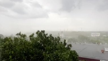 Şiddetli yağmur ve güçlü rüzgarlar şehirdeki ağaçları ve binaları darmadağın eder. Sağanak sisli bir atmosfer yaratır ve fırtınalı havada çatılar görülebilir. Dramatik ve yoğun bir yaz fırtınası.