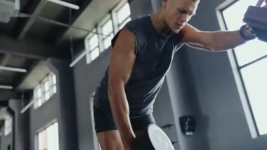 Endüstriyel bir spor salonunda yoğun bir şekilde çalışan bir adam. Spor yaparken çaba gösteriyor, azmini gösteriyor ve fiziksel gücünü gösteriyor..