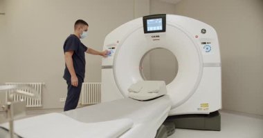 Olgun doktor teknik ekipmanları ayarlar. Tıptaki modern teknolojiler. Modern hastanenin ışık laboratuarına kurulmuş modern CT makinesinin sol ve sağ görüntüsünü kaydır