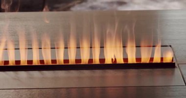 Close-up artificial electronic fireplace burning with smoke fire. Bio fireplace burn. Modern smart ecological alternative technologies Interior design of house inside. Electric modern fireplace