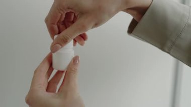 Birinin eline beyaz bir şişeden tek bir hap dökerken çekilmiş yakın plan fotoğrafı. İlaç ve sağlık sigortası kavramlarını ön plana çıkarıyor. El Doğal Işıkta Beyaz Şişe 'den Bir Hap Alırken
