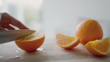 Tahta kesme tahtasında taze portakalı dilimleyen bir elin sağlıklı yemek ve yemek pişirmeyi vurguladığı detaylı bir görüntüsü. Tahta bir yüzeyde Yeni Portakallar Kesen Elin Yakın Çekimi