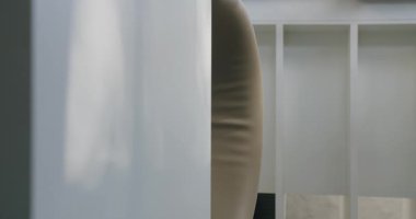 Çağdaş minimalist bir iç mekânın yakın bir görüntüsü. Beyaz dokulu bir duvara karşı parlak ahşap bir raf. Basitliği ve tarzı somutlaştırıyor. Minimalist İç Tasarım, Dikey Video.