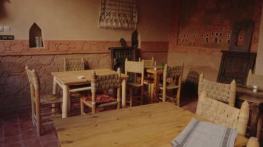 Geleneksel Fas kafe iç mimarisi ahşap masalar, dokuma sandalyeler ve yerel dekorasyonlar. Bu büyüleyici restoran otantik bir kültürel yemek deneyimi sunuyor. Sıcak ve davetkar atmosfer.