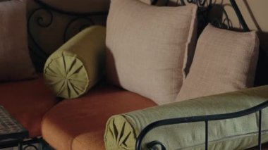 Dekoratif yastıkları ve yastıkları olan rahat bir dinlenme odası. Bu Fas 'tan esinlenilmiş oturma düzeninde rahatlama ve sohbet için sıcak ve davetkar bir ortam sunuluyor. dekor geleneksel ögeleri