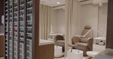 Zarifçe tasarlanmış modern manikür salonu şık sandalyeler, iyi organize edilmiş tırnak cilası rafları ve sofistike ışıklandırma. Rahatlatıcı bir güzellik deneyimi için mükemmel..