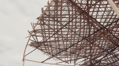 Bulutlu bir günde bambu tepe örtüsünü kapatın. Birlikte oluşturulan çubuklar güzel kafesler oluşturuyor. Tropik kaçamak, güneş koruması ve rahatlama. Gölge yapısı için kullanılan doğal malzemeler.