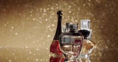 Zarif parfüm şişelerinden oluşan bir koleksiyon pırıl pırıl altın arka planda, lüks, klas ve sofistike çağrıştırıyor. Güzellik, parfüm ve lüks temalı projeler için mükemmel..