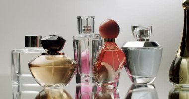 Çeşitli parfüm şişelerinin şık bir koleksiyonu. Yansıtıcı bir yüzeyde zarif bir şekilde sergileniyor. Farklı şekiller ve renkler sergileniyor. Zarif Parfüm Şişeleri Koleksiyonu