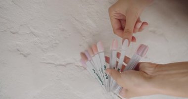 Palette tırnak cilası örnekleri var. Manikür için vernik örneklerinin toplanması. Manikür tırnağı renginde palet tutan kadın elleri. Tırnakların güzelliği ve sağlığı. Polonya örneklerini çivile.