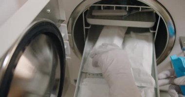 Klavyeden sterilizasyon sonrası bireysel kraft paketlemedeki manikür aletlerini çıkartırken eldiven kadına yakın çekim. Tırnak bakımı işlemleri için kadın hazırlama araçları.