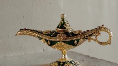 Süslü, altın ve yeşil Aladdin 'in sihirli lambası. Dilekleri, hayalleri ve iyi kaderi temsil ediyor. Fas 'tan gelen dekoratif bir hatıra merak, sihir ve doğu kültürünü çağrıştırıyor. Peri masalları