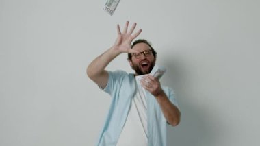 Havaya para saçan heyecanlı bir adam. Açık mavi bir gömlek ve beyaz bir tişört giyiyor. Adamın gözlüğü ve sakalı var. O mutlu ve zenginliğini kutluyor..