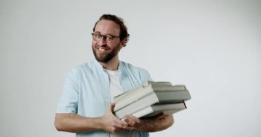 Bir adam kitap yığınını tutarken kaslarını esnetir, okuma gücünü ve sevgisini gösterir. Kameraya gülümsüyor, edebi uğraşlarına güveni ve gururu tam..