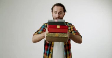 Neşeli bir adam bir yığın hediyeyi tutar ve onlara gülümseyerek bakar. Bu hediyeleri aldığı için heyecanlı ve mutlu. Hediye vermek, kutlamalar, tatiller ya da doğum günleri için mükemmel..