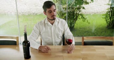 Şarap yapma konsepti. Şarap üreticisi şarap tadıyor. Camın dönüşü şarabın yüzeyini dalgalandırıyor ve uzun cam duvarlar boyunca uzanıyor. Sommelier şarap kadehini sallıyor ve tadına bakıyor.