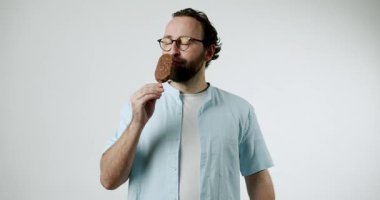 Mavi gömlekli bir adam çikolatalı dondurmaya dalmış. Her lokmanın tadını çıkarıyor, ziyafetin tadını çıkarıyor. Klasik dondurulmuş tatlıyla basit, tatmin edici bir zevk. Yaz için mükemmel.,