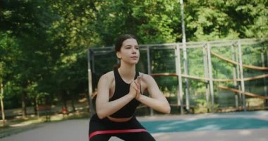 Sıska kadın dışarıda lastik bantla mindere çömeliyor. Aktif yaşam tarzı. Crossfit sağlıklı konsept. Lastik bant bacak esnetme egzersizi yapmak için dört ayak kasları kasmak için..