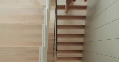 Modern Home 'daki yaşlı adam dikkatle ahşap merdivenlerden iniyor. Yaşlı bir adamın ihtiyatlı bir şekilde ahşap merdivenlerden aşağı inerek yaşlanma ve ev güvenliğinin özünü yakaladığını görüyorum..