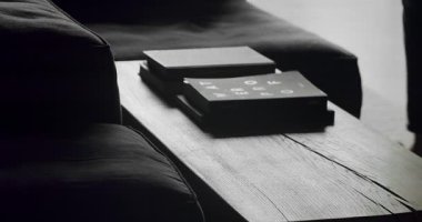 Adam masanın yanında yürür ve siluetler ve gölgeler yaratır. Köşedeki kanepe ve kitaplığı olan lüks modern ev iç mimarisi. Moda mobilyalar. Minimalist Ev İçi.