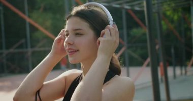 Kadın sabah antrenmanından sonra müzik dinliyor. Beyaz Kulaklıklı Müzik Dinleyen Genç Sporcu Kadın. Boş zaman. Mutlu, spor ve müzik dinleyen kişinin portresi.