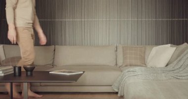 Orta yaşlı bir adam, modern bir oturma odası ortamında kitap okumaya dalmış şık, gri bir koltukta dinleniyor. Rahat adam evde modern gri kanepe üzerine kitap okuyor.