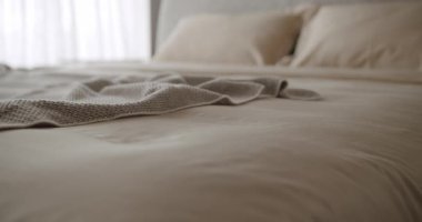 Huzur dolu bir yatak odasında yumuşak örülmüş battaniyeli rahat bir yatak görüntüsü. Rahatlama, rahatlama ve ev dekorasyonuyla ilgili kavramlar için mükemmel. Yatak odası dinleniyor.