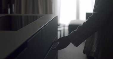 Bir kişi siluette parlak pencereli loş bir odada çekmece açarken görülüyor. Atmosfer sakin ve gizemli. Dimly Lit Room 'da Parlak Işıklı Kişinin Silueti
