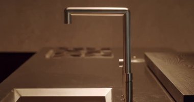 Pürüzsüz, çağdaş bir mutfak musluğunun, karanlık mutfak tezgahına karşı minimalist bir tasarımı var. Modern ev detaylarına odaklan. Modern Mutfak Musluğu Çağdaş Ev Tasarımı