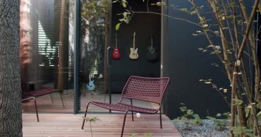 Modern ev terasında sandalyeler. Ev stüdyosunun kapısının ve camdan duvarın yanındaki terasa yerleştirilmiş rahat sandalyelerin sağ görüşünü yansıt. Zarif oturaklı açık hava verandası