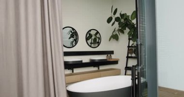 Dairesel aynalar, ev bitkileri ve minimalist raflarla donatılmış çift gösterişli modern banyo. İşlevsellik ve tarzın mükemmel bir karışımı. Küvetli modern banyo..