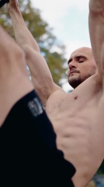 Kaslı bir adam açık hava spor salonundaki yatay bir barda barfiks çekiyor. Formuna ve gücüne odaklanıyor. Formunu gösteriyor. Fitness, sağlık ve egzersiz videoları için ideal.