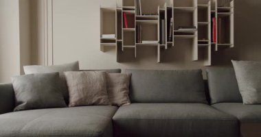 Çağdaş oturma odası, parlak gri bir kanepe ve eşsiz geometrik kitaplık düzeniyle. Şık ve minimalist iç mimari modern evler için mükemmel. Tarz sahibi Gri Koltuklu Modern Oturma Odası