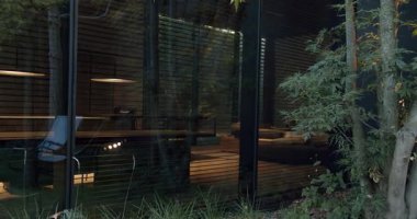 Ahşap duvarları ve çevre aydınlatmasıyla sakin bir akşam penceresinden çekilen şık bir ev ofisine bir bakış. Modern İçişleri Ofisi Konforlu Gece Penceresinden Geçer