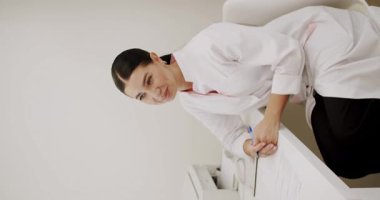 Profesyonel bir kadın evrakları imzalamak için öne eğiliyor, iyi aydınlatılmış, modern bir ofis düzenine güveni ve coşkuyu yayıyor. Modern Ofiste Profesyonel Kadın İmza Belgeleri. Dikey video.